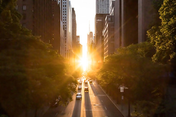 Sunlight shines on the buildings and cars along 42nd Street through Midtown Manhattan around the Manhattanhenge sunset in New York City