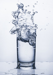 Glass with splashes of water. Splashing water. Copy space.