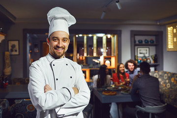 A male cook is smiling against the background of a restaurant.