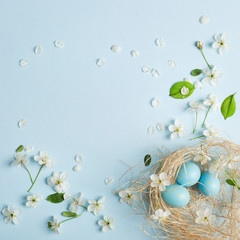 painted blue Easter eggs in the nest on the background of cherry blossoms