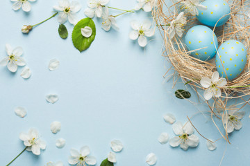 painted blue Easter eggs in the nest on the background of cherry blossoms