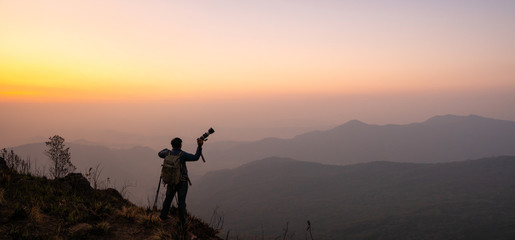 photographer celebrating success on top of a mountain in a majestic sunrise