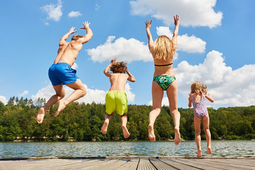 Glückliche Familie springt in einen See