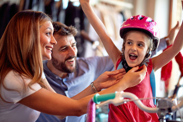 Family buying new bicycle for little girl in bike shop .