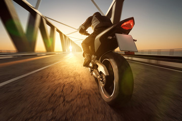Motorrad fährt über Brücke im Sonnenuntergang