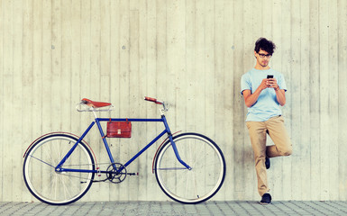 people, communication, technology, leisure and lifestyle - hipster man with smartphone and fixed gear bike on city street