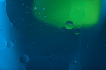 Abstract blurred background. The texture of the fluid with circles, lines and drops of green and blue. Cropped shot, macro, horizontal, nobody, free space for text.