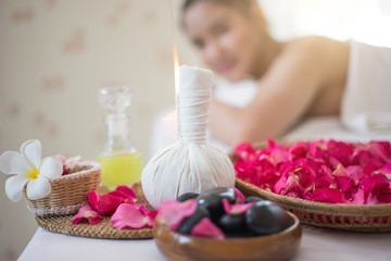 Spa concept: zen stones, candles and flowers on the background of woman receiving treatment