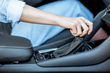 Woman switching gear, holding handle of the automatic gearbox of the modern car, close-up view