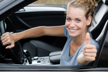 cute woman giving thumb up inside her car