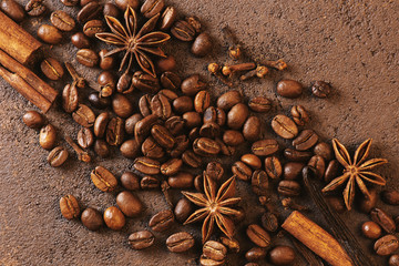 Coffee beans and spices on the textured brown table