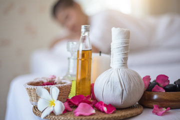 Spa concept: zen stones, candles and flowers on the background of woman receiving treatment