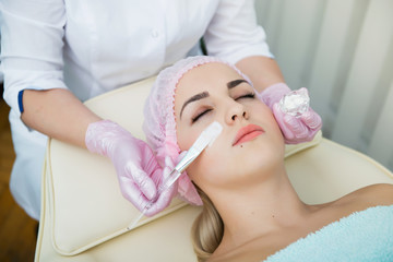 spa, cosmetologist applying cream mask on face