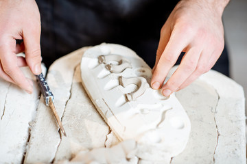 Male worker getting clay products from the gypsum forms at the pottery manufacturing, close-up view