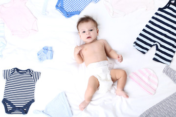 Cute baby with fashion clothes lying on white bed