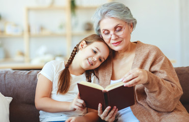 happy family grandmother reading to granddaughter book at home