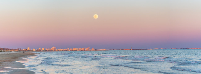 panorama sur une plage avec la lune au coucher de soleil