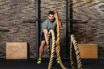 Athlete workout with battle rope at gym