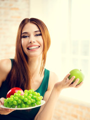 Smiling woman with plate of fruits, indoors
