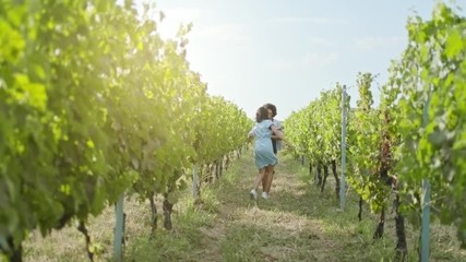 Romantic love couple walking and playful running thru green vineyards. Front follow wide shot.Friends italian trip in Umbria.4k slow motion