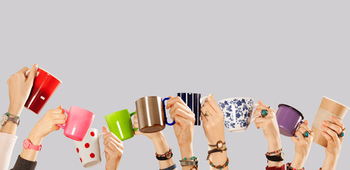Many different arms raised up holding coffee cup