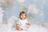 Cute little angel sitting in the clouds