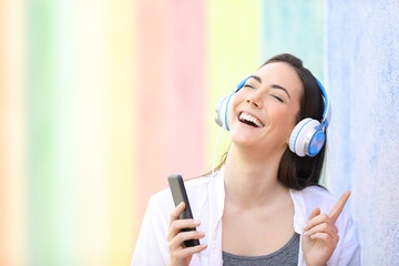 Happy girl singing listening to music in a colorful street