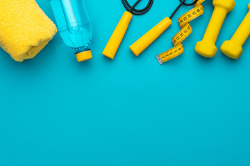 flat lay photo of yellow fitness equipment in oder over turquoise blue backgound