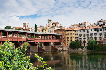colorful houses  along river Brenta in Bassano del Grappa, Italy. With reflection in water and old wooden bridge
