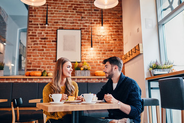 Picture of young couple at cafe. Young woman and man at coffee shop.