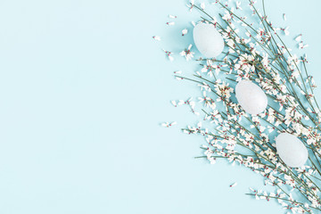Easter composition. Easter eggs, white flowers on pastel blue background. Flat lay, top view, copy space