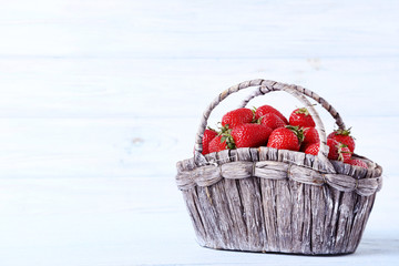 Fresh strawberries in basket on wooden table