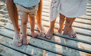 Legs and feet of family standing on beach on summer holiday, a midsection.