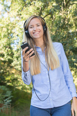 young woman listening enjoying music in forest