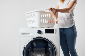 Partial view of woman with landry basket and washing machine isolated on grey