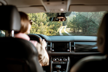 Woman driving car on the forest road, view from the car interior