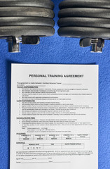 Personal training agreement next to dumbbells on a blue velvet background