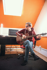 A man in glasses working with guitar in the studio