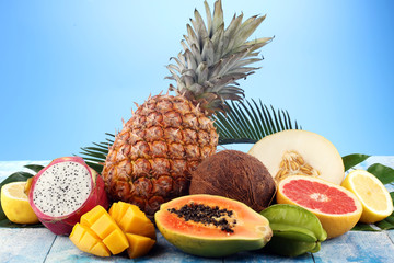 Fresh tropical Fruits on the beach with a palm leave. Assorted tropical fruits, orange,Ananas or pineapple and mango