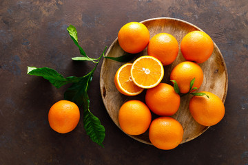 Oranges with leaves on dark background, top view