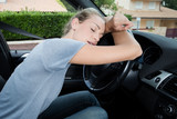 tired woman sleeping on steering wheel in car