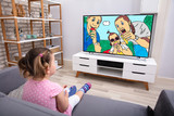 Little Girl Sitting On Sofa Watching Cartoon