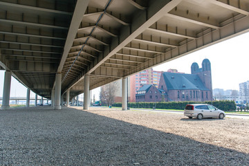 view from under a modern automobile bridge next to a beautiful historic building