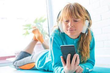 woman in sportswear listening to music with phone and headphones
