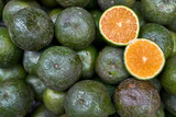 Ripe sliced citrus lying on pile of green oranges