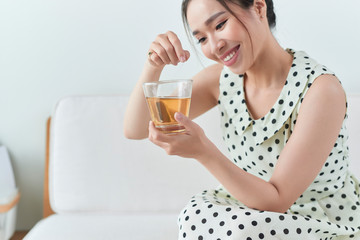 Happy asian woman sitting on her sofa holding cup at home