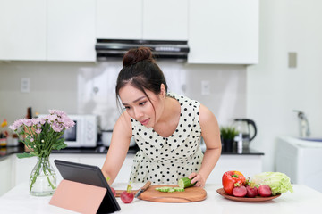 woman using tablet while making a healthy salad at the kitchen