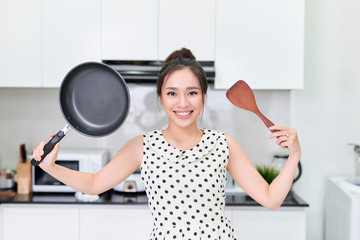 Young woman showing a pan and a spatula