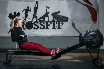 woman exercising in gym crossfit training rowing machine