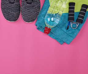 femal sports sneakers and a  water bottle on a pink background